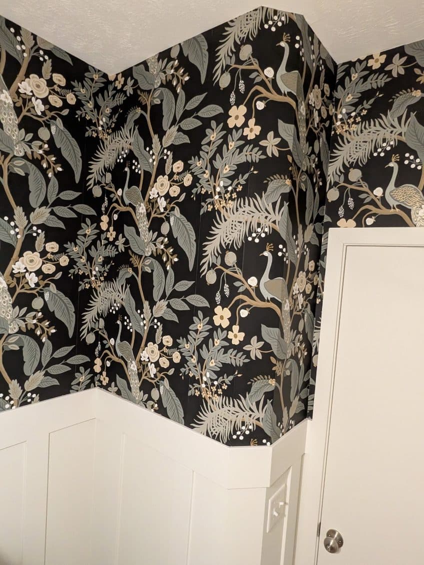 A powder bathroom with dramatic dark botanical wallpaper, expertly installed