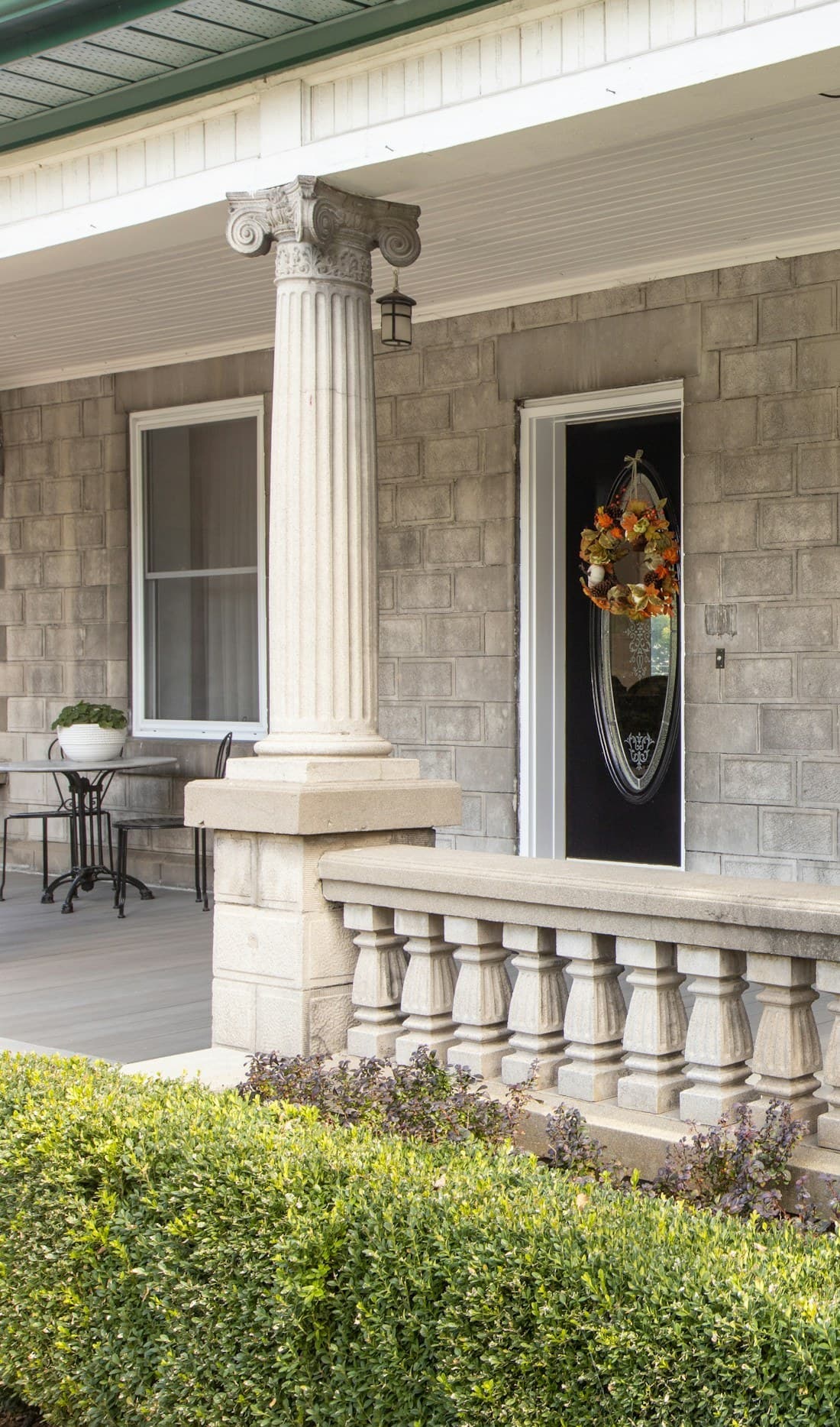A classic covered porch entry with a painted door and stone column